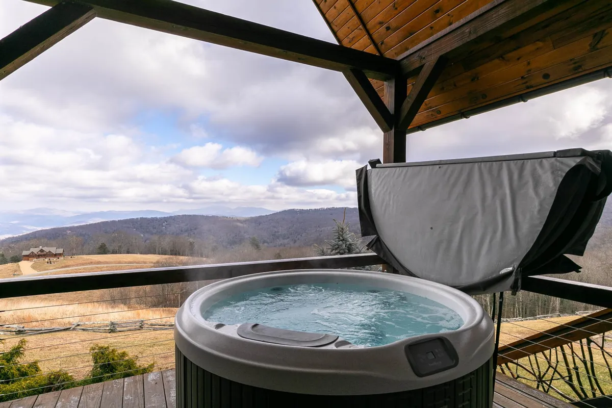 A serene exterior view showing a bubbling hot tub set on the deck, with a sweeping mountain vista in the background. The outdoor space is tranquil, emphasizing the relaxing environment and connection to nature that guests and their pets can appreciate together.