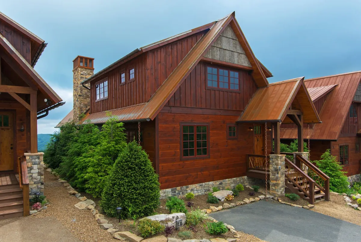 The hero image showcases a beautifully crafted wooden cabin with a striking stone chimney, nestled along a landscaped path. The setting is warm and inviting, ideal for outdoor gatherings, with hints of mountain views and natural surroundings that evoke a sense of peaceful seclusion.