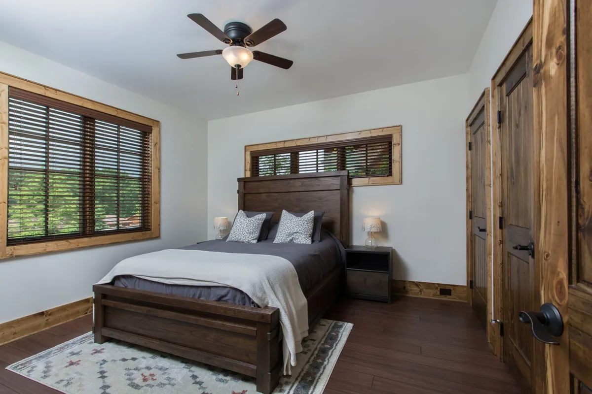 A serene bedroom featuring a comfortable bed with crisp linens, matching nightstands, large windows allowing in natural light, and wood accents throughout, creating a cozy and inviting atmosphere ideal for relaxation.
